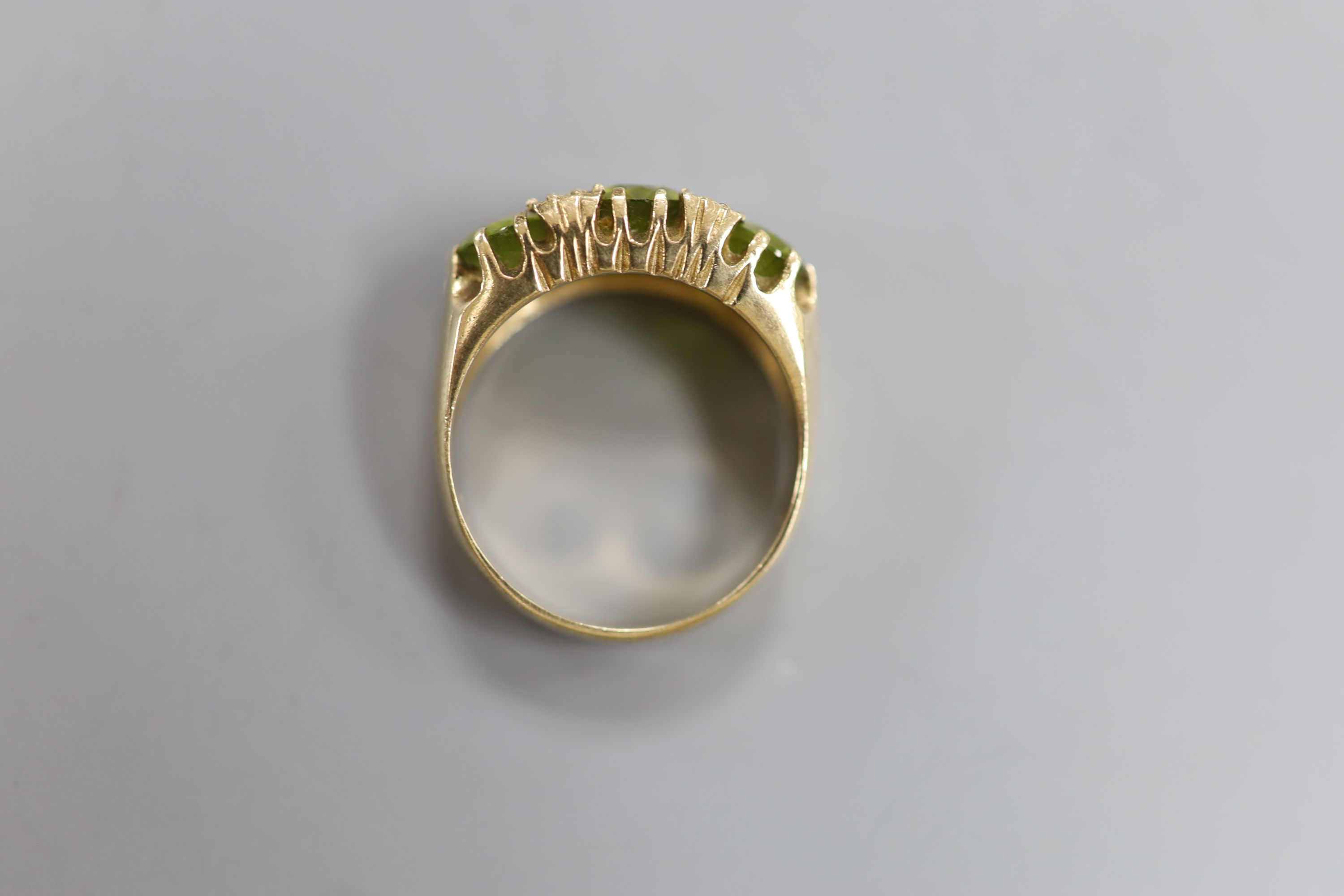 A modern 9ct gold, three stone peridot and diamond chip set dress ring, size P, gross 6 grams.